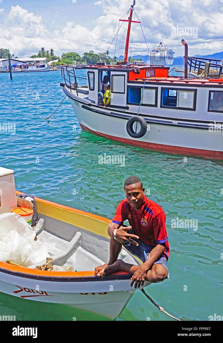 Giovane uomo su una barca al porto di Alotau su Milne Bay, Papua Nuova Guinea. Foto Stock
