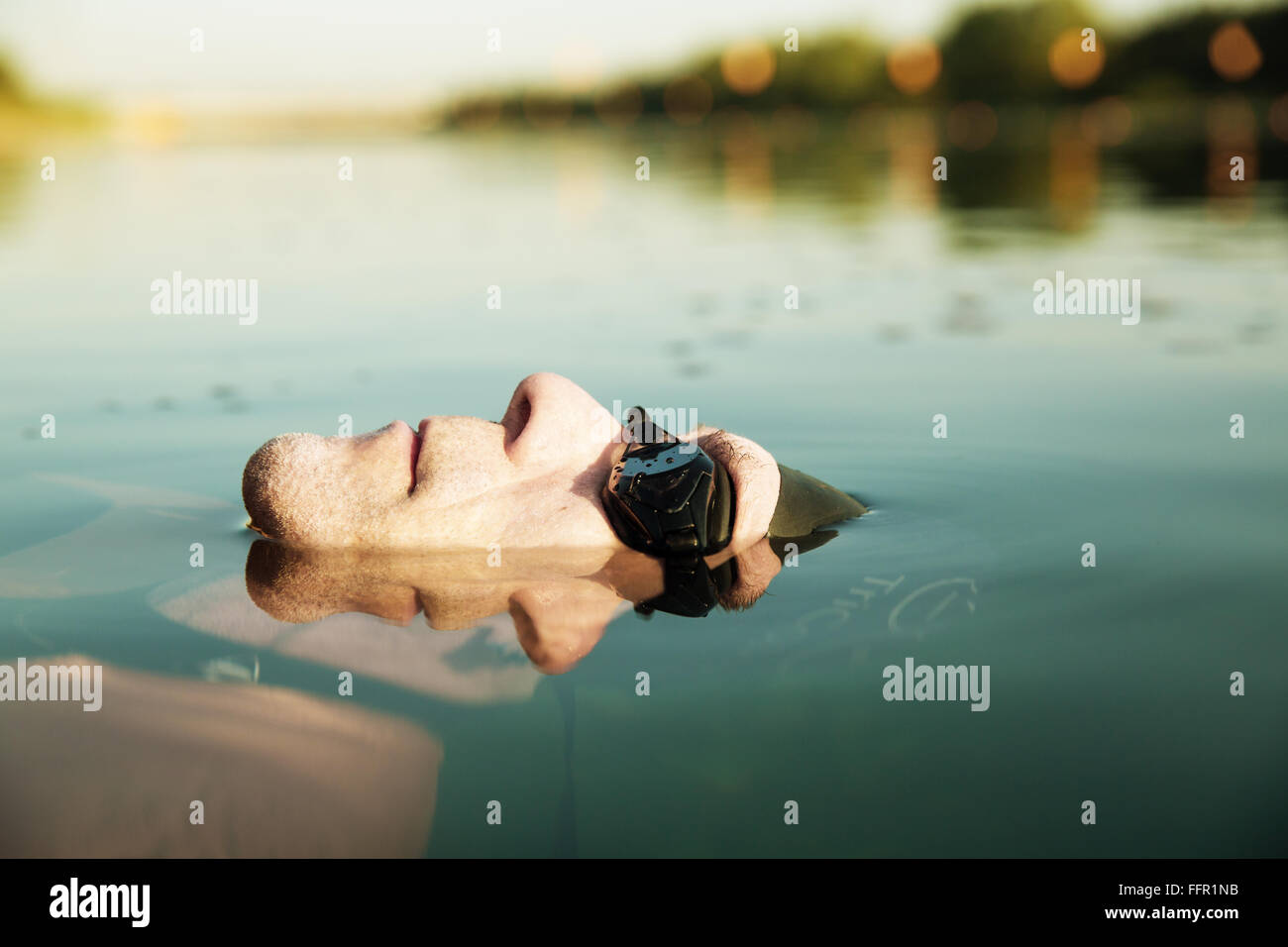 Uomo con gli occhiali per nuoto, testa mezza immersi nel lago, Germania Foto Stock