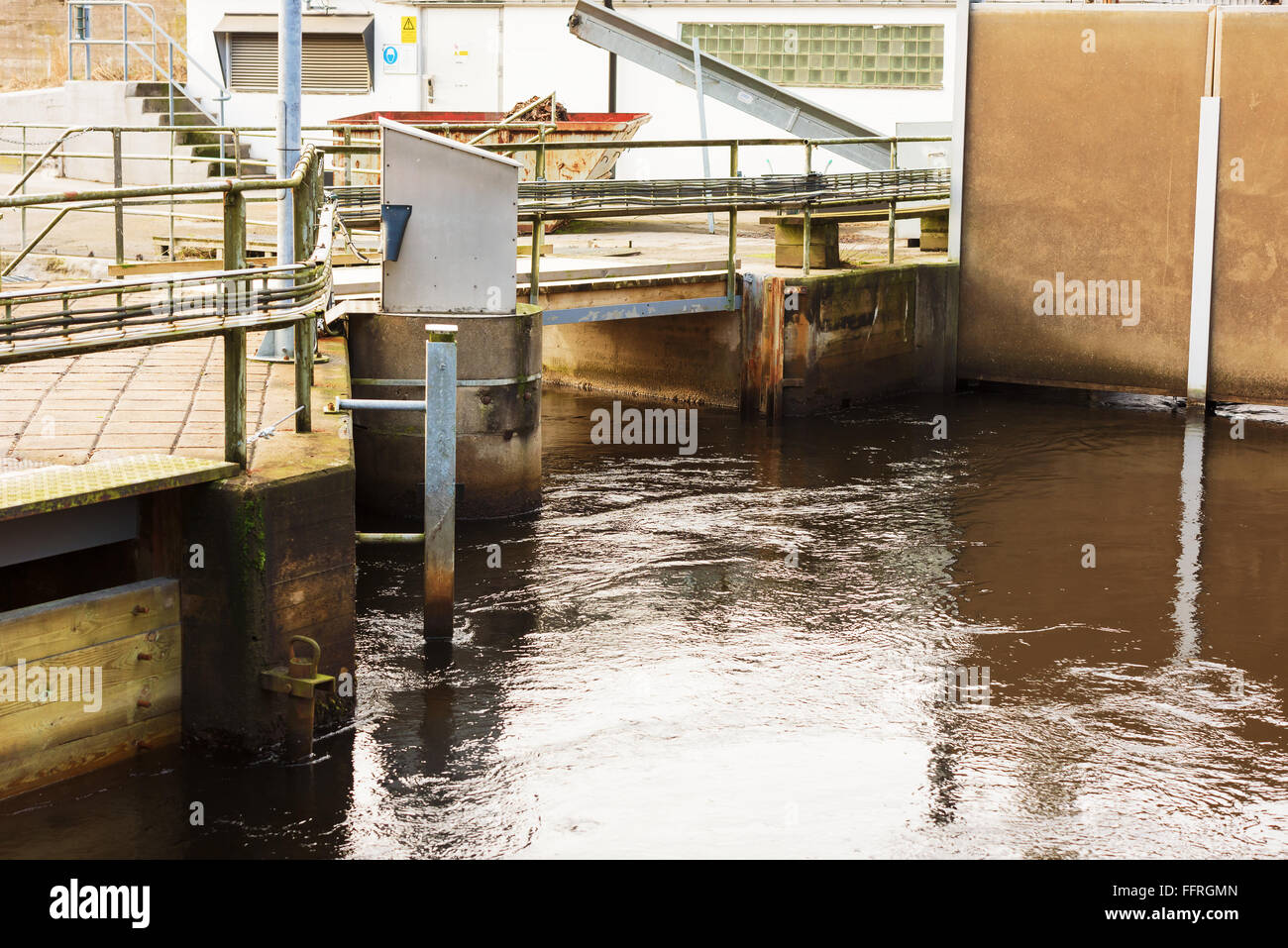 Djupafors, Svezia - Febbraio 07, 2016: un piccolo ponte che attraversa oltre la piccola diga idroelettrica. Lo streaming di acqua è costretto a re Foto Stock