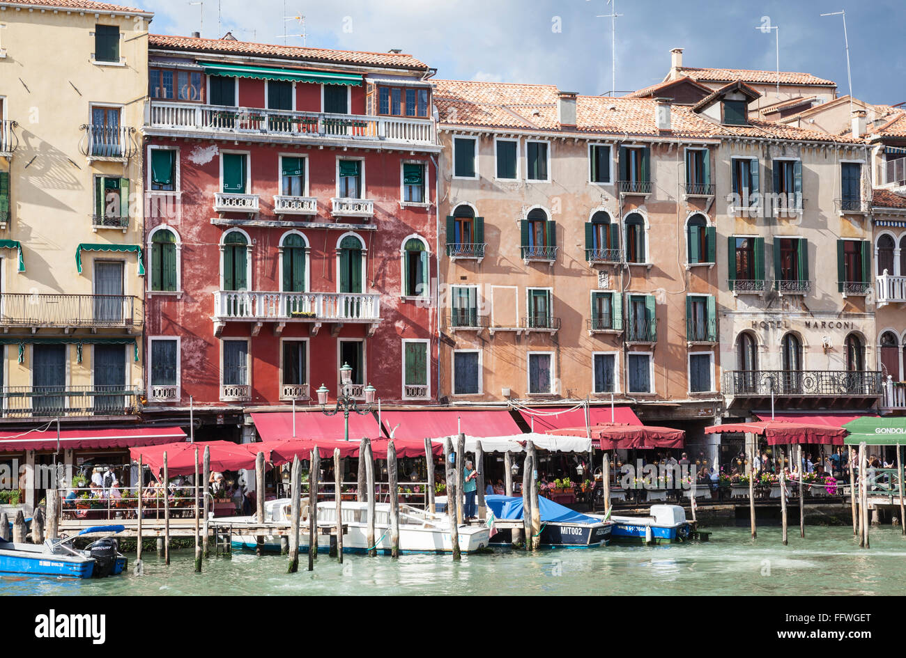 Classici edifici veneziani, ormeggi delle barche e caffè in una giornata di sole lungo il Canal Grande a Venezia Foto Stock