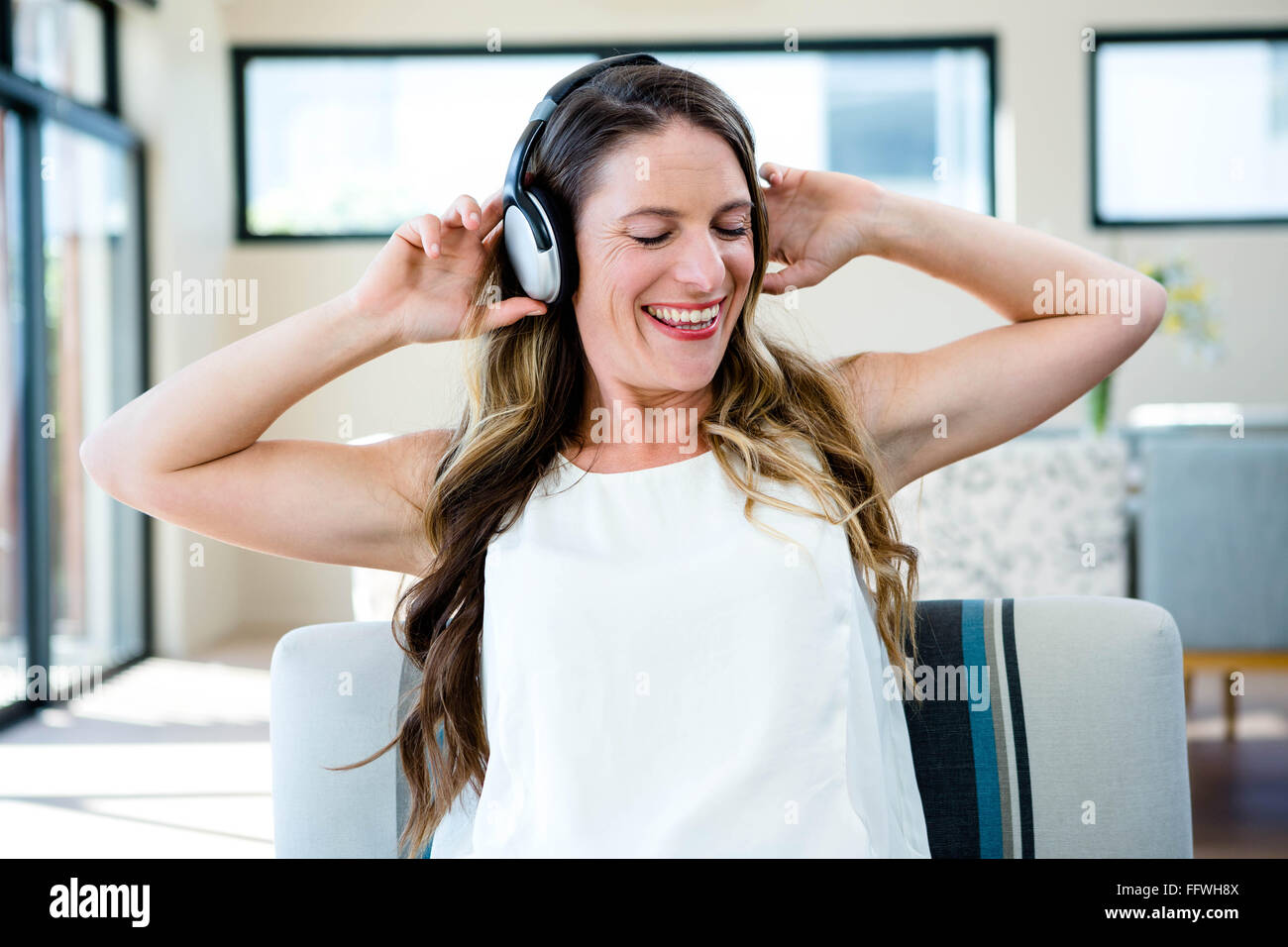 Donna sorridente ascoltando la sua musica su cuffie Foto Stock