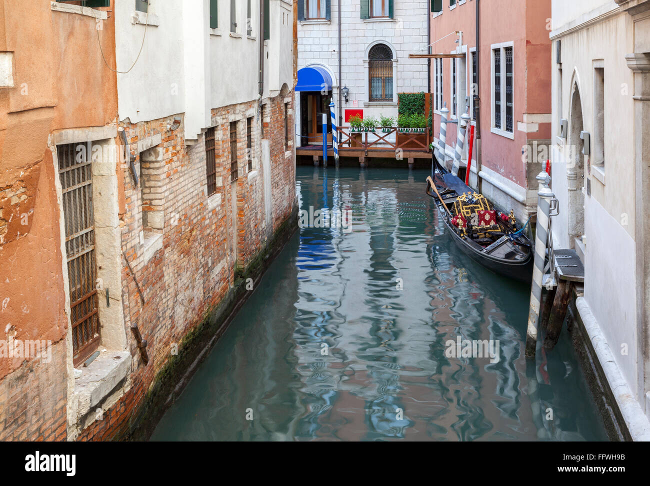 Zona isolata e tranquilla di Venezia con una gondola ormeggiata e riflessioni di vecchi edifici Foto Stock
