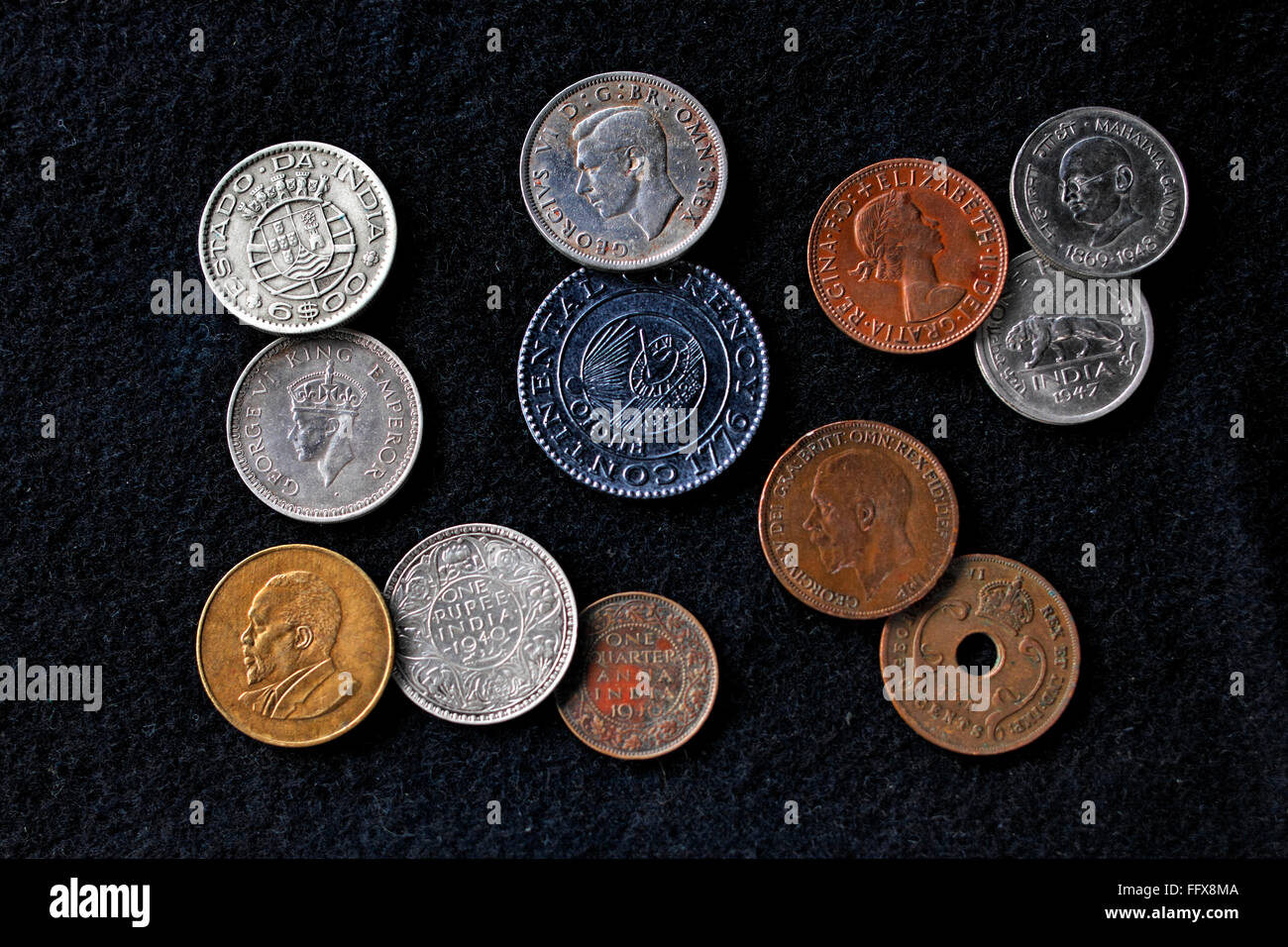 Monete vecchie, monete indiane, monete rotonde, monete metalliche, monete britanniche, monete d'argento, monete d'ottone, monete di bronzo, monete con foro, fondo nero, India Foto Stock
