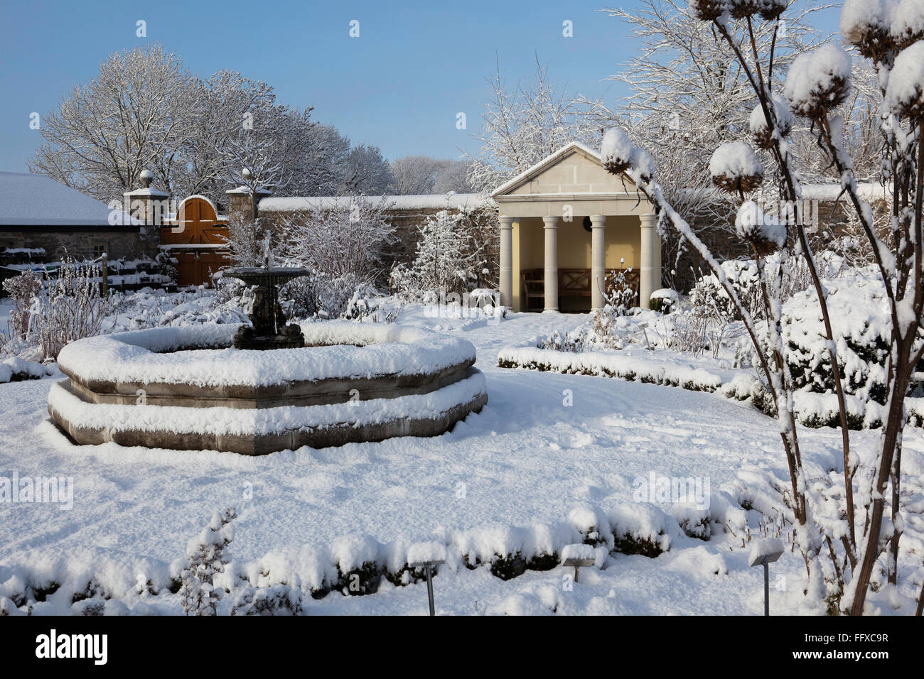 Fontana centrale di Cowbridge Physic Garden coperto di neve sotto un cielo blu chiaro Foto Stock