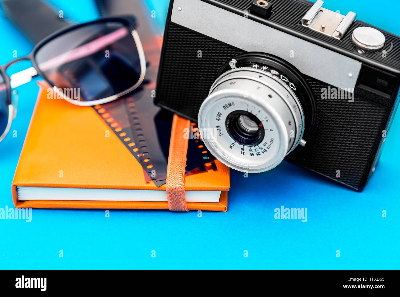 Vecchia fotocamera retrò,la striscia del film,occhiali da sole e album di foto su sfondo blu Foto Stock