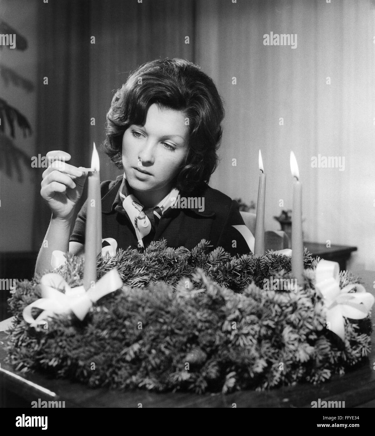 Natale, stagione dell'avvento, donna che illumina le candele sulla corona dell'Avvento, circa 1970, diritti aggiuntivi-clearences-non disponibile Foto Stock