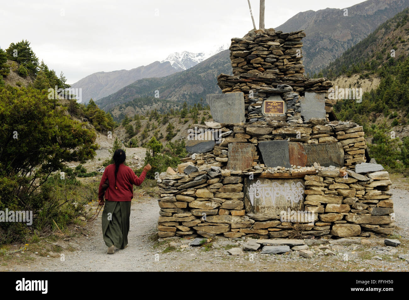 Donna adorare struttura in pietra ; Braka ; Nepal Foto Stock