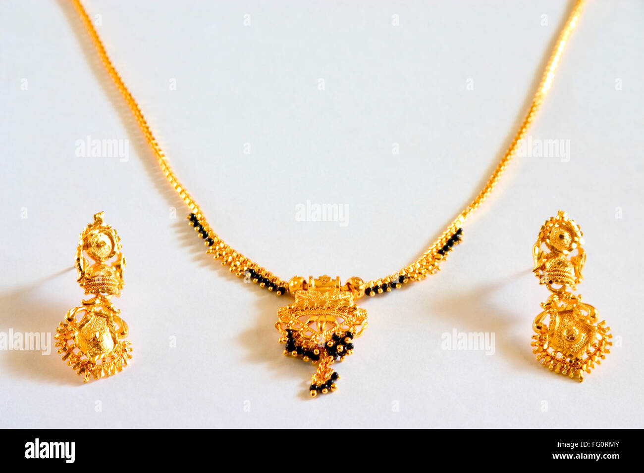 oro nero perline collana gioielli mangalsutra indiano indù sposa simbolo matrimonio oro orecchini artificiale imitazione gioielli sfondo bianco India Foto Stock