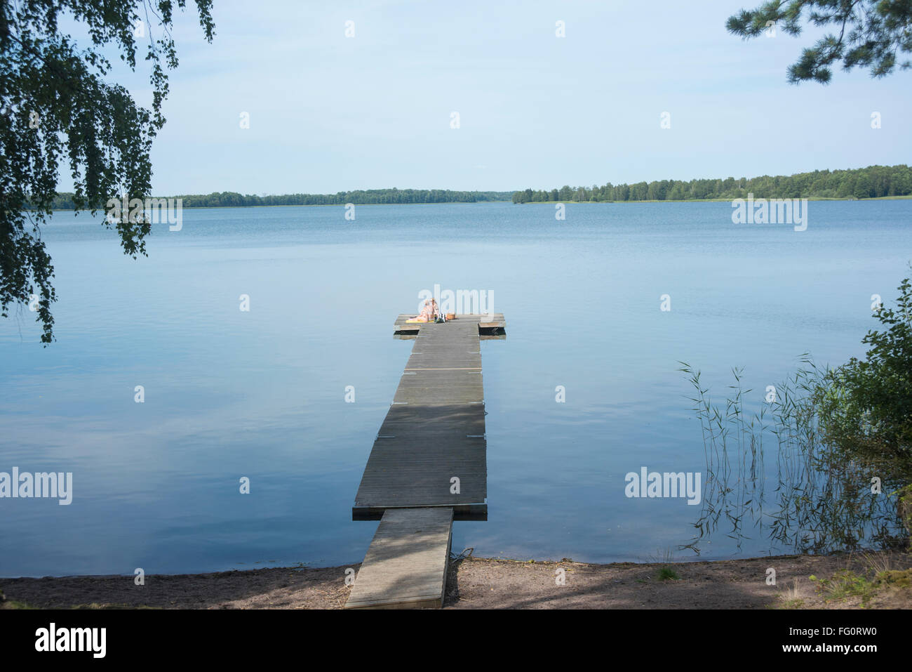 Due signore a prendere il sole su un molo nel lago Långsjön in Björklinge, vicino a Uppsala, Svezia Foto Stock