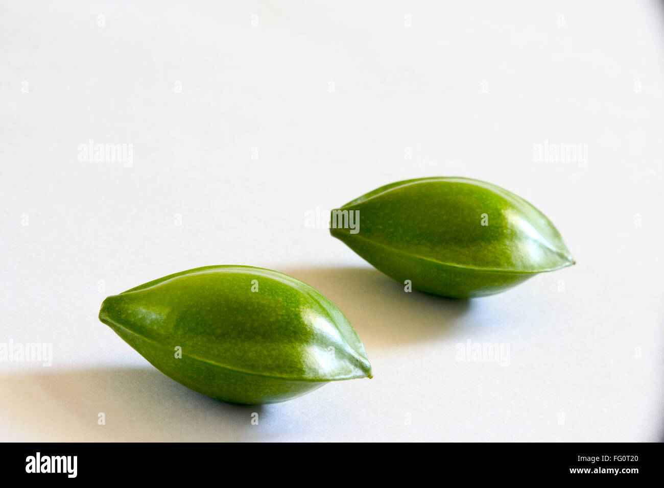 Frutta , due occhi verde mandorla sagomato badam Prunus dulcis su sfondo bianco Foto Stock