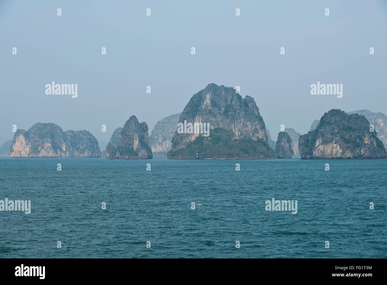 Misty immagine di pietre calcaree carsiche o isole che sorge fuori del mare nella baia di Halong, nel Vietnam del Nord, Gennaio Foto Stock