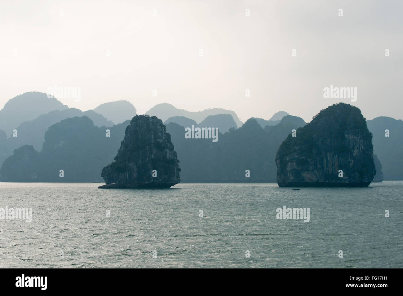 Misty immagine sfuggente di pietre calcaree carsiche o isole che sorge fuori del mare nella baia di Halong, nel Vietnam del Nord, Foto Stock