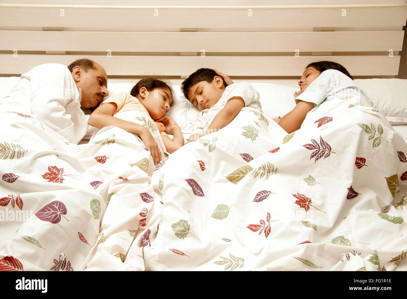 South Asian Indian famiglia ideale avente suono addormentato sul letto signor#86E,191,686d,189 Foto Stock