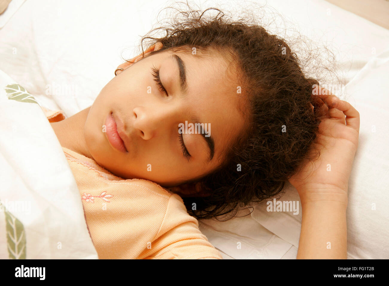 South Asian Indian 9 anni ragazza indossando peach colore avente nightwear suono addormentato sul letto signor#191 Foto Stock