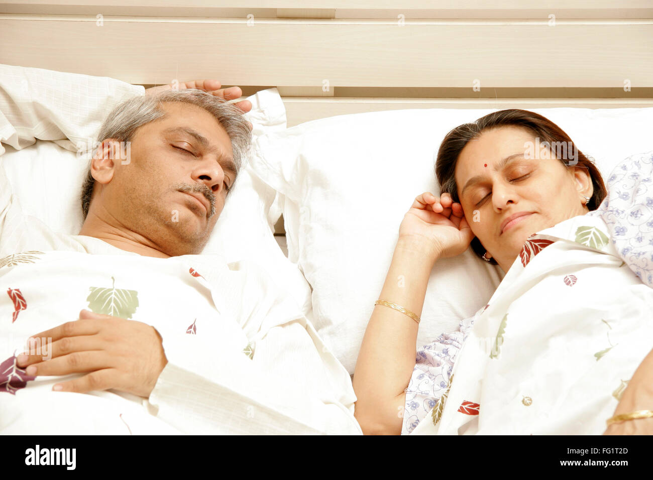 South Asian Indian Coppia di mezza età avente suono addormentato sul letto signor#686F,646 Foto Stock