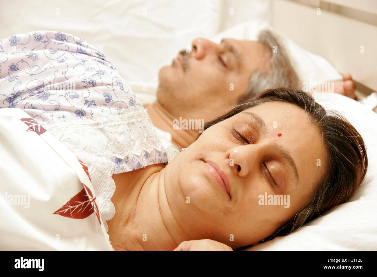 South Asian Indian Coppia di mezza età avente suono addormentato sul letto signor#686F,646 Foto Stock