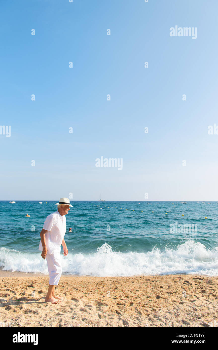Senior uomo che guarda il mare con surf sulle rocce Foto Stock
