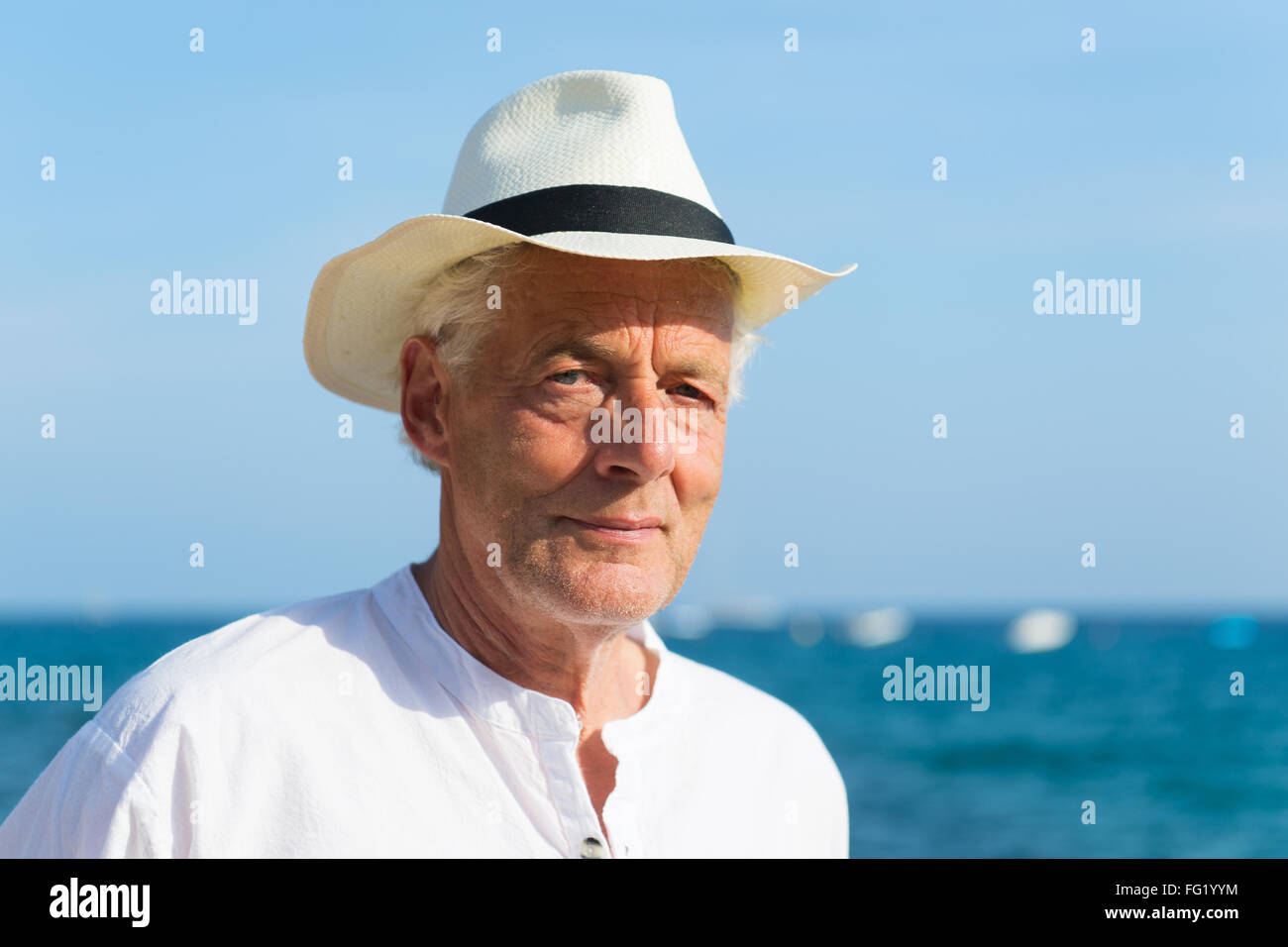 Senior uomo che guarda il mare con surf sulle rocce Foto Stock