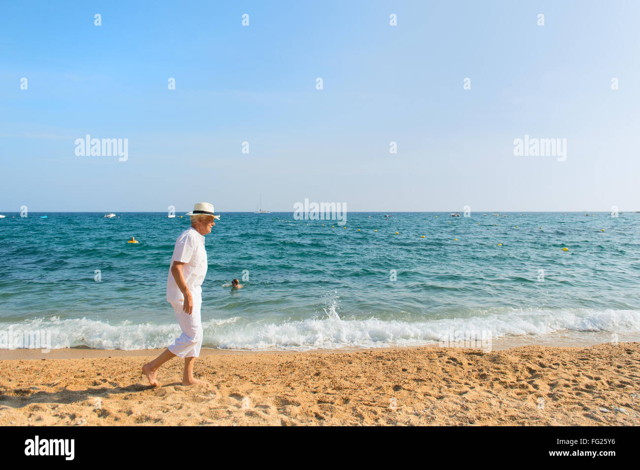 Senior uomo in abito bianco a piedi la spiaggia Foto Stock