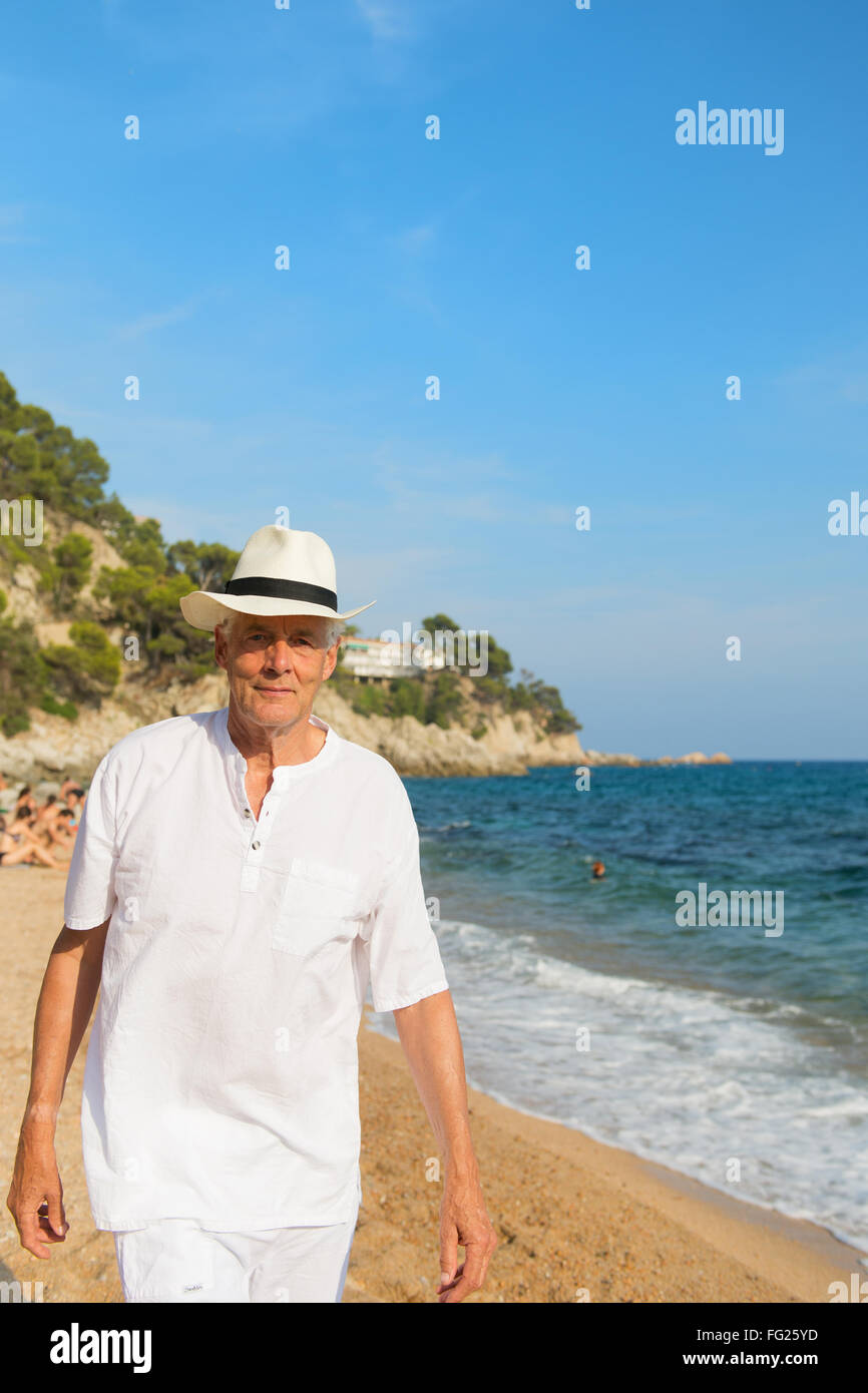 Senior uomo in abito bianco a piedi la spiaggia Foto Stock