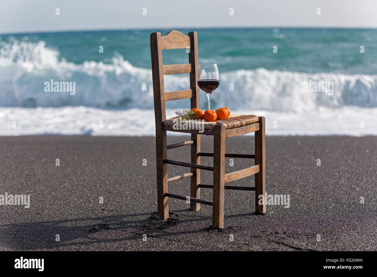 Vino e tangerini su una sedia contro il mare Foto Stock