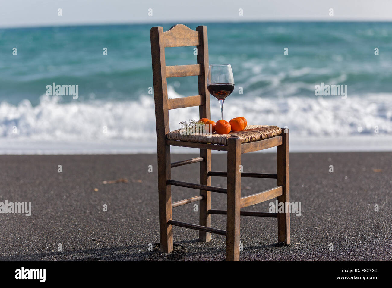 Vino e tangerini su una sedia contro il mare Foto Stock