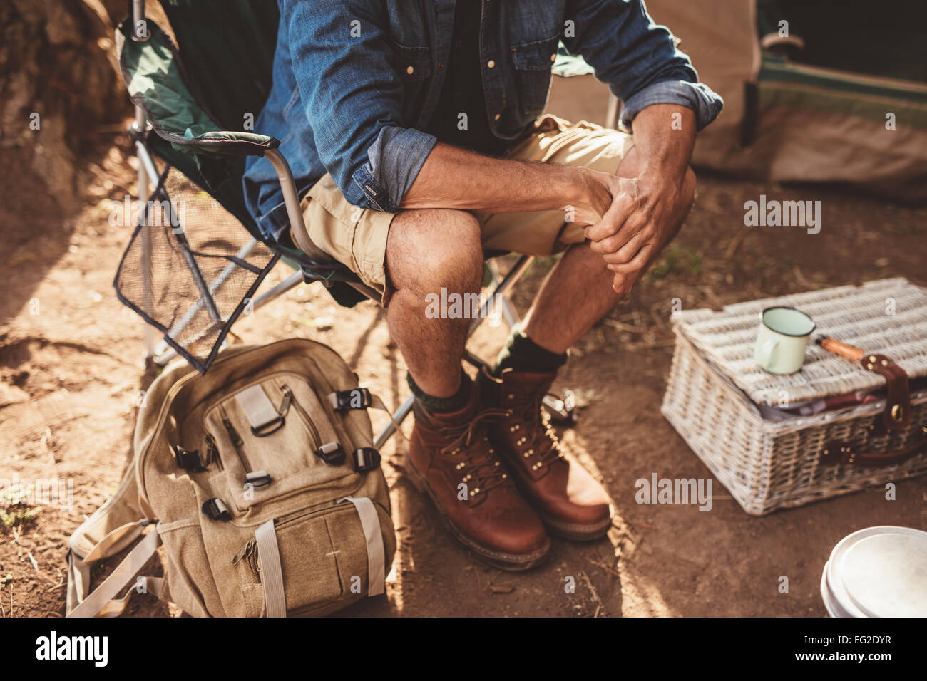Immagine ravvicinata di uomo maturo seduto su una sedia. Uomo relax al campeggio, concentrarsi sulle mani. Foto Stock