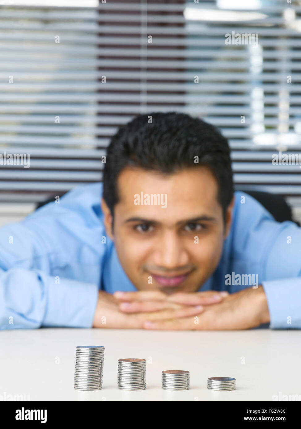 Executive toccando mento su entrambi le mani osservando mucchio di monete signor #779K Foto Stock