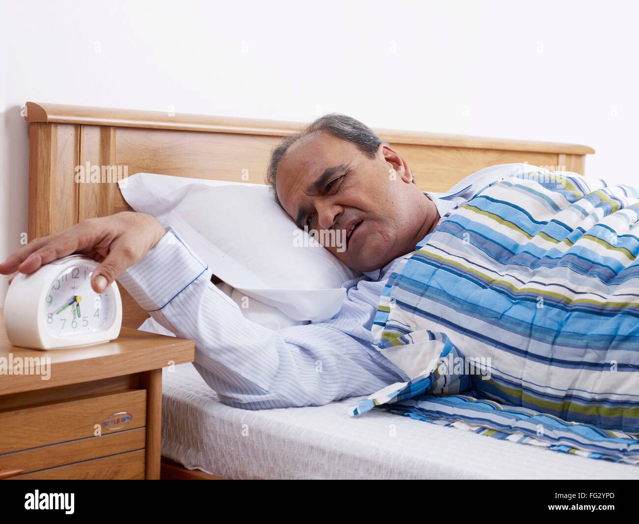 Il vecchio uomo reclinata su letto di arresto a mano la Suoneria sveglia signor#702T Foto Stock