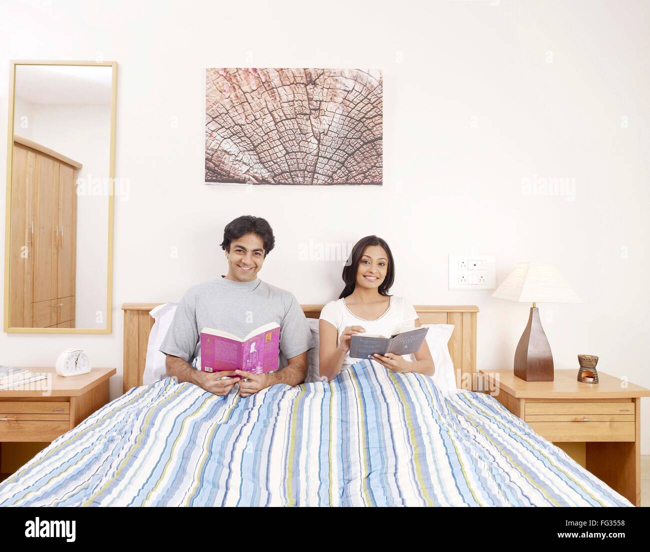Giovane uomo e donna azienda romanzi seduta sul letto signor#702V,702U Foto Stock