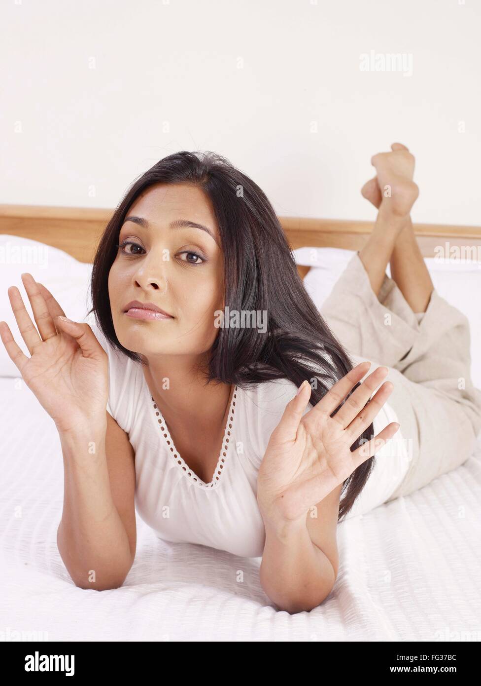 Signora giovane esprimendo con le mani la posa sul letto signor#702U Foto Stock