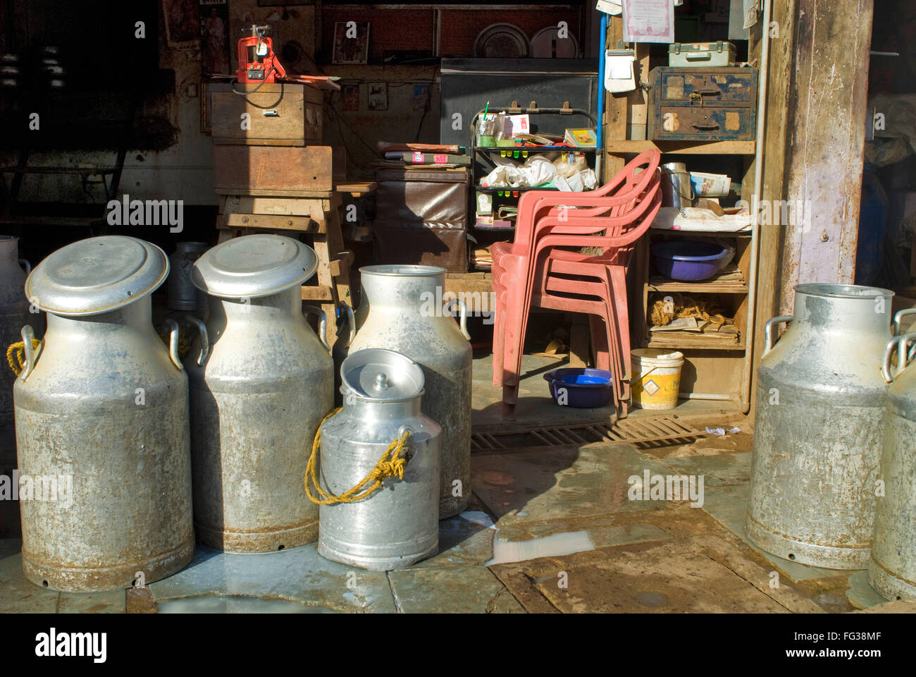 Red sedie di plastica e alluminio lattine di latte in Mahesh Dairy Doodh Kendra ; Bhuj ; ; Kutch Gujarat ; India Foto Stock