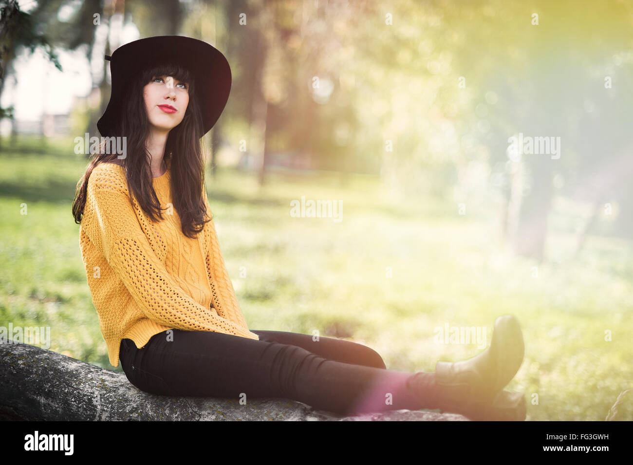 Ritratto di un brunnete felice e sorridente ragazza in un cappello nero e giallo maglione Foto Stock