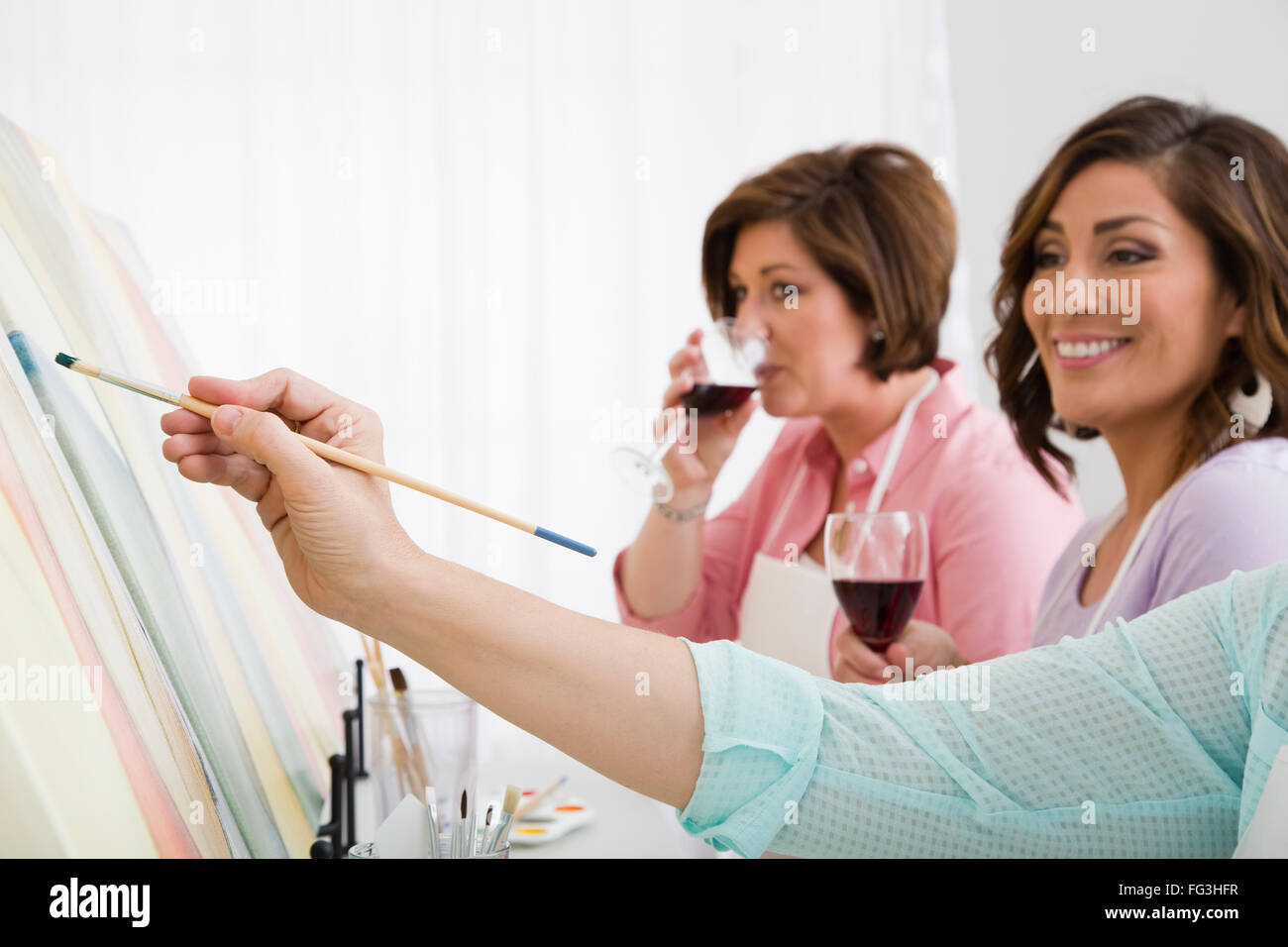 Tre donne pittura e bere il vino Foto Stock