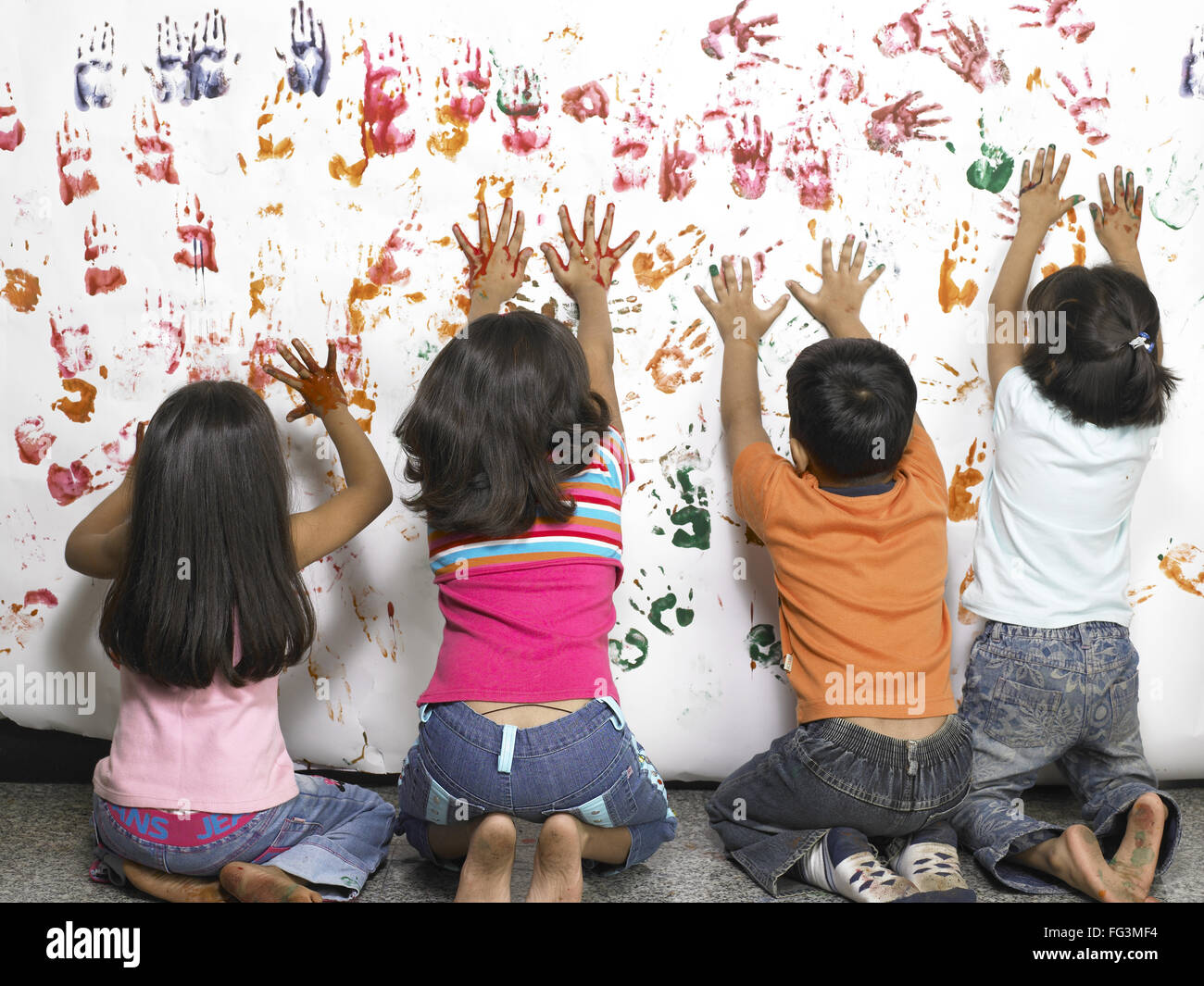 Ragazzo e ragazze rendendo handprint acquerello su carta nella scuola materna - Modello rilasciato Foto Stock