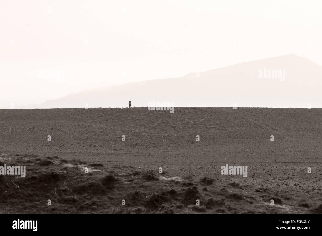 Distante uomo in piedi sul plateau sulle colline in Azerbaigian. Un senso di scala e di piccolezza in colline non lontano da Baku Foto Stock