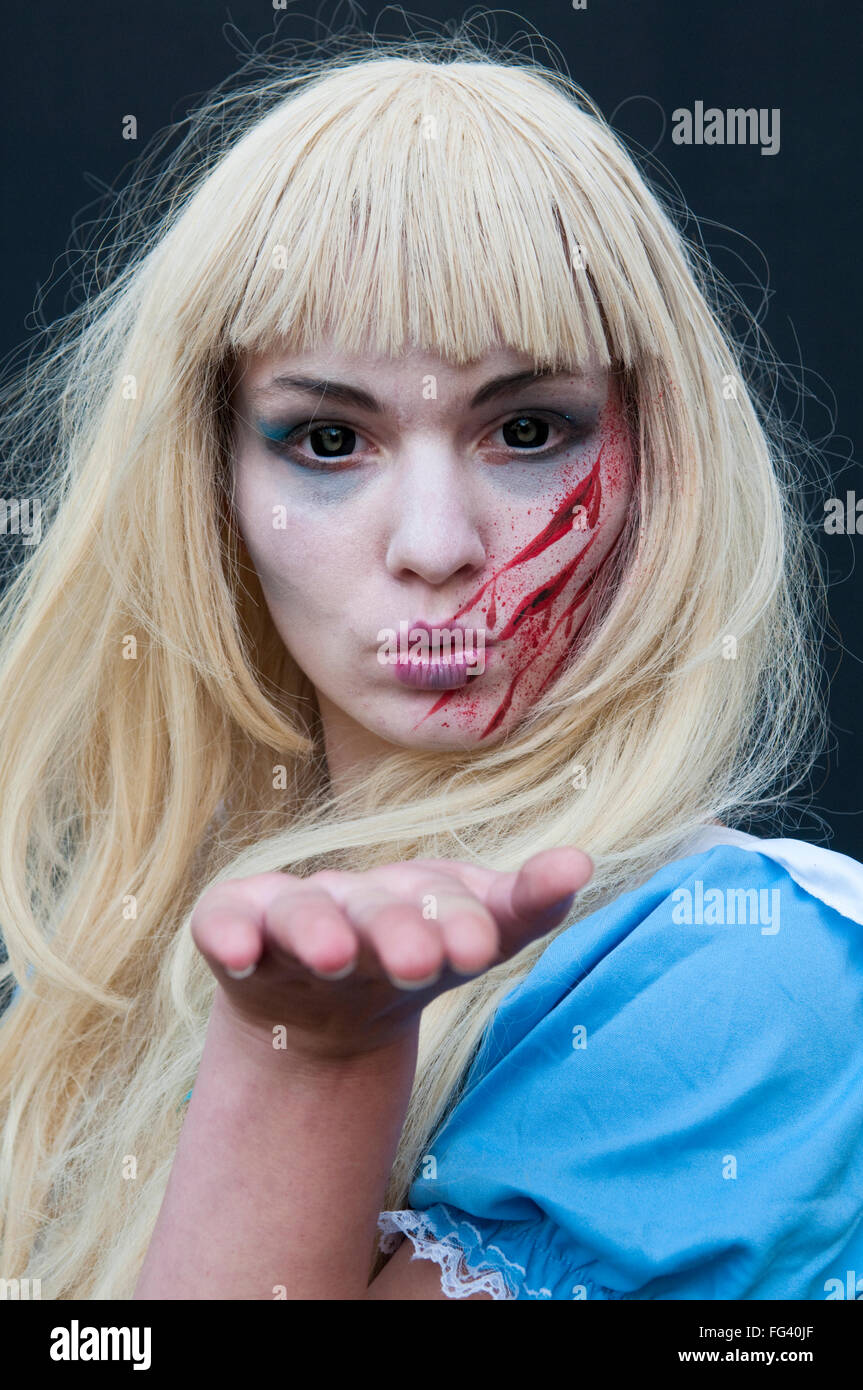 Una donna realizzata fino ad assomigliare a una paura di Alice nel Paese delle Meraviglie zombie come personaggio soffia un bacio Foto Stock