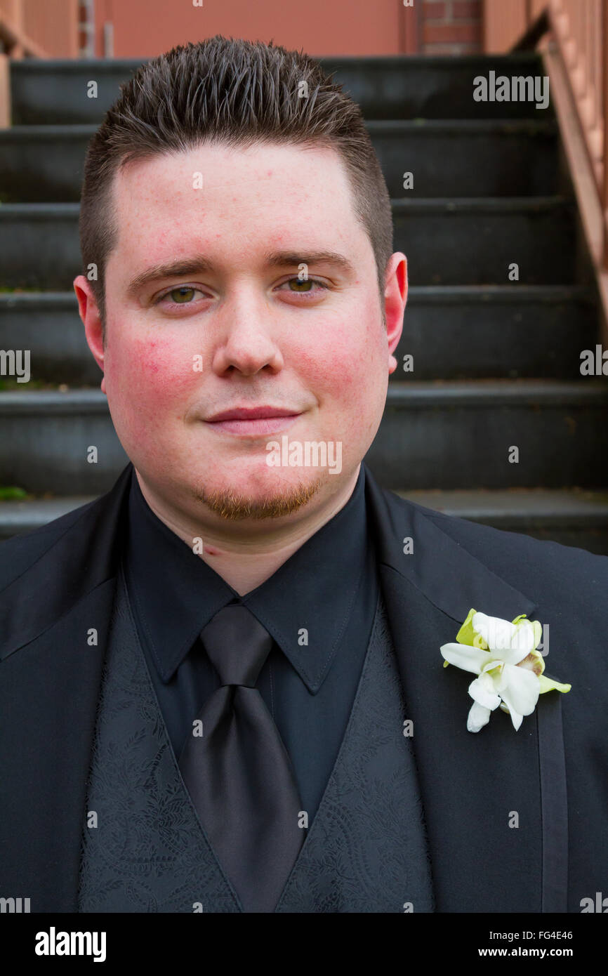 Lo sposo in posa per un ritratto all'aperto sul suo giorno di nozze in Oregon, indossando un nero tux. Foto Stock