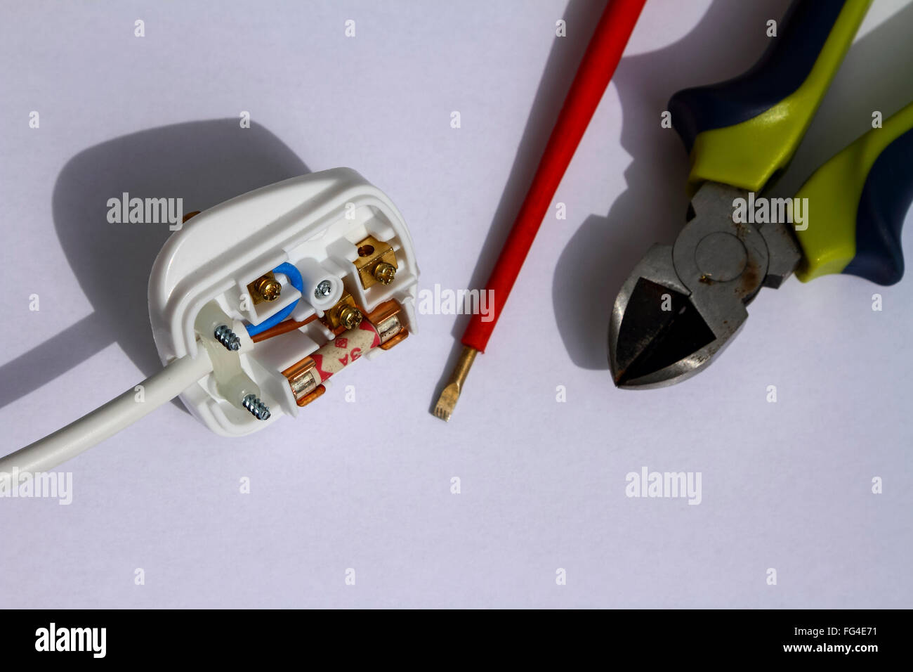 Elettrico di rete 240 volt plug montato con un fusibile da 3 amp ed elettricamente isolato cacciavite e pinze isolate su uno sfondo bianco Foto Stock