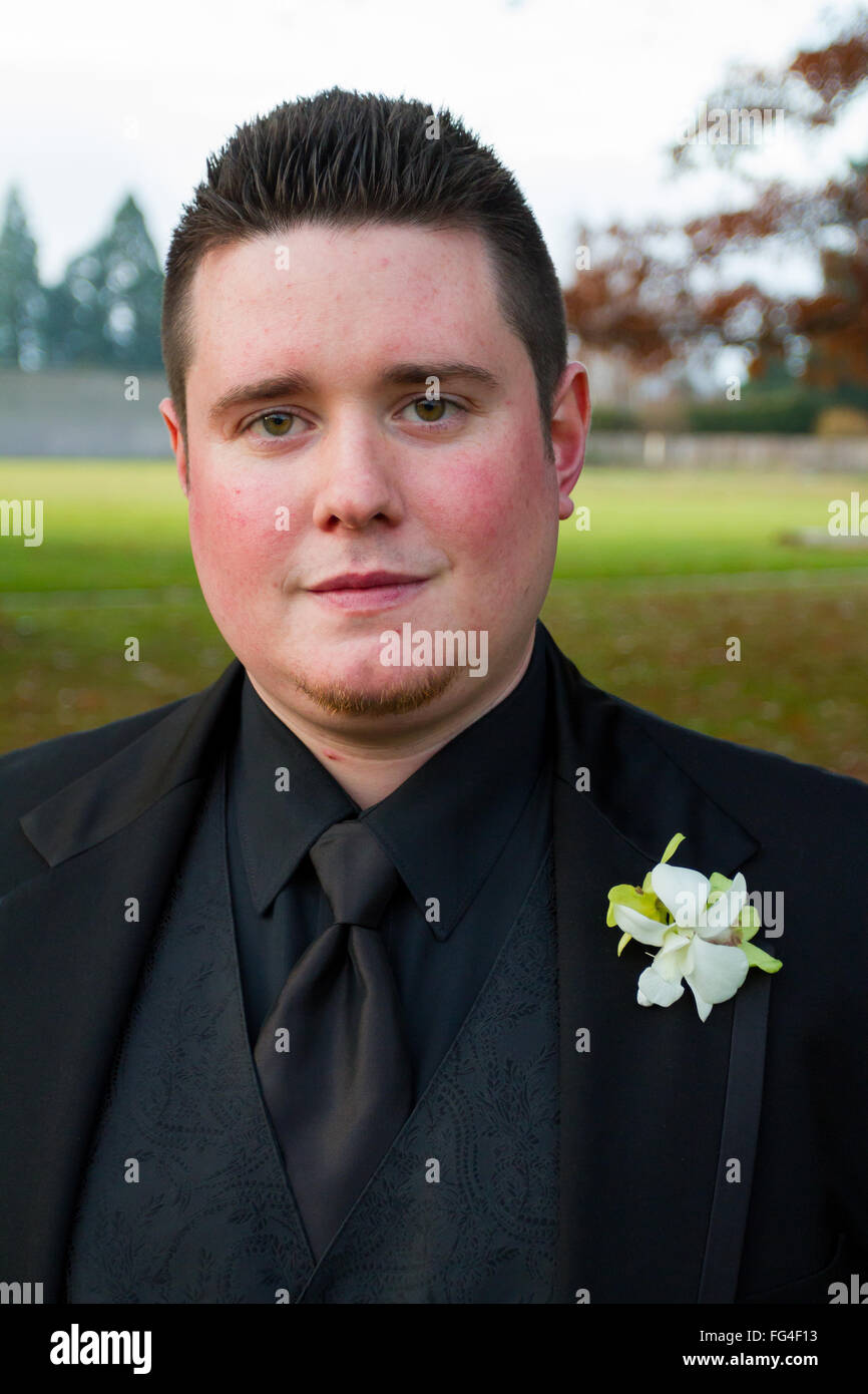 Lo sposo in posa per un ritratto all'aperto sul suo giorno di nozze in Oregon, indossando un nero tux. Foto Stock
