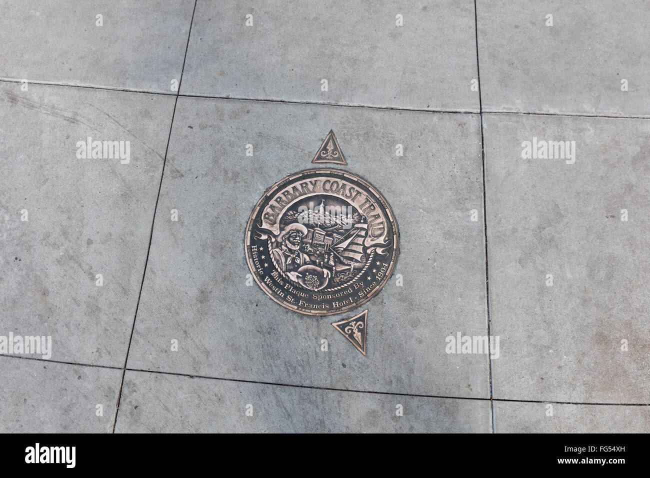 Medaglione di bronzo e frecce incorporato nella marcatura sul marciapiede di Barbary Coast Trail del sito storico di San Francisco, CA Foto Stock