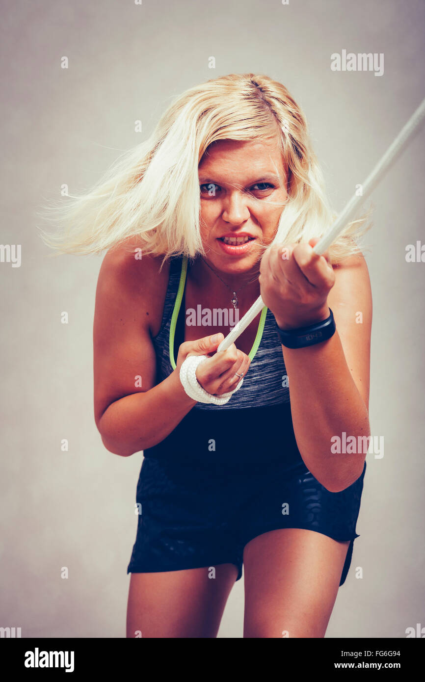 Fiducioso forte donna sportivo tirando la fune. Determinazione, di sforzo e di potere femminile nozione. Foto Stock