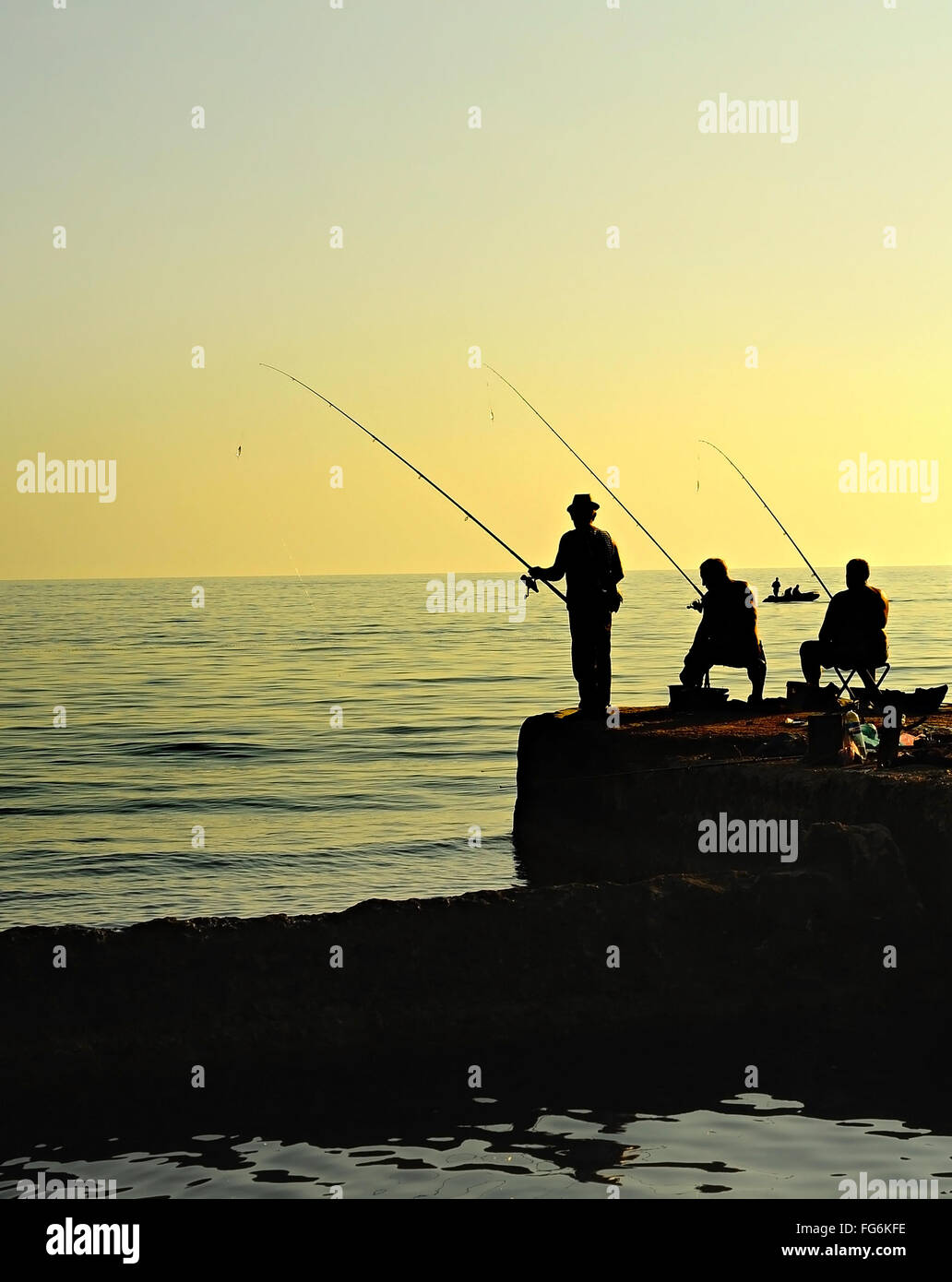 Gruppo di pescatori su un molo al tramonto. Penisola di Crimea Foto Stock