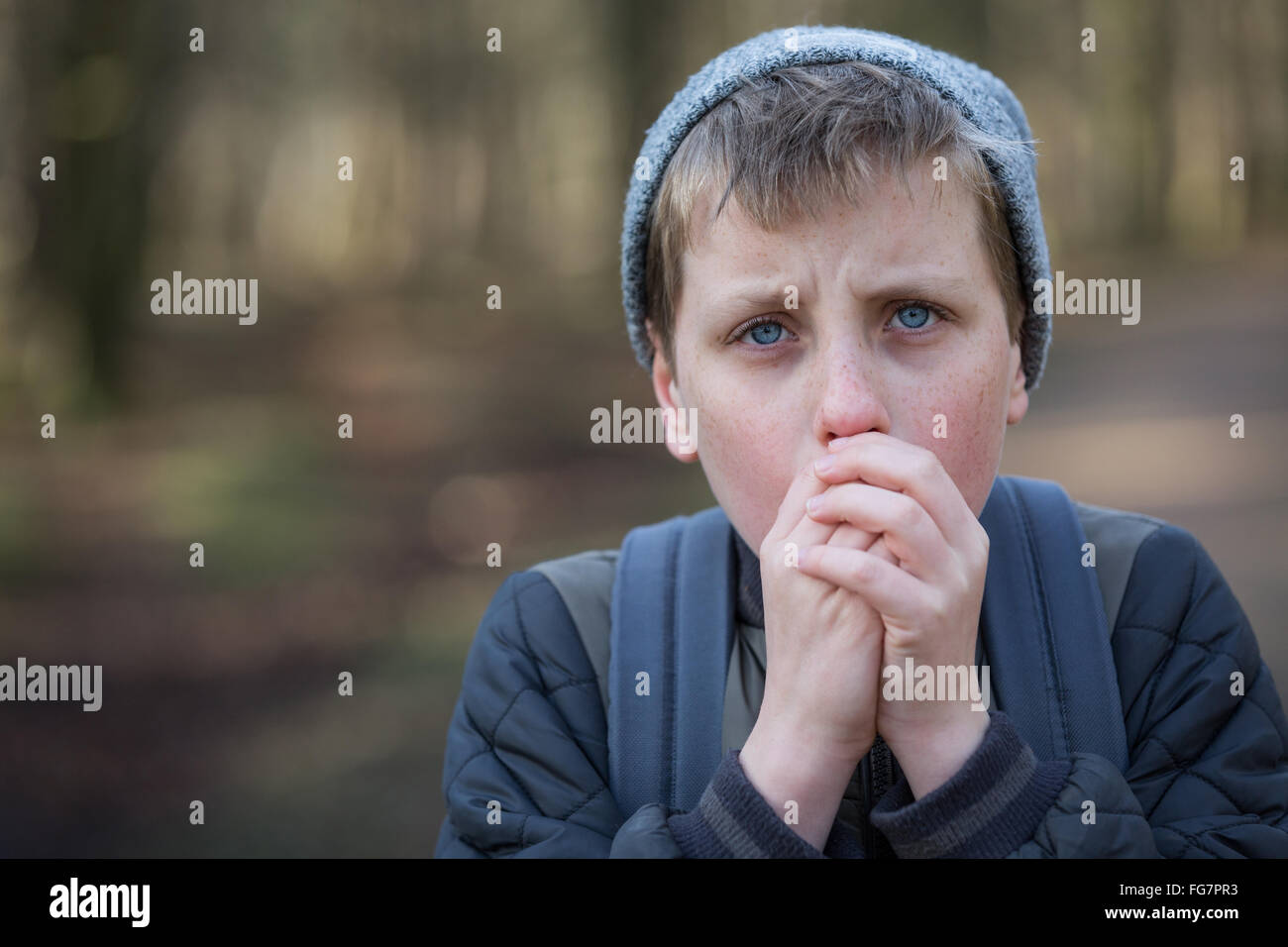 Un ragazzo freddo nei boschi cercando di tenere in caldo Foto Stock