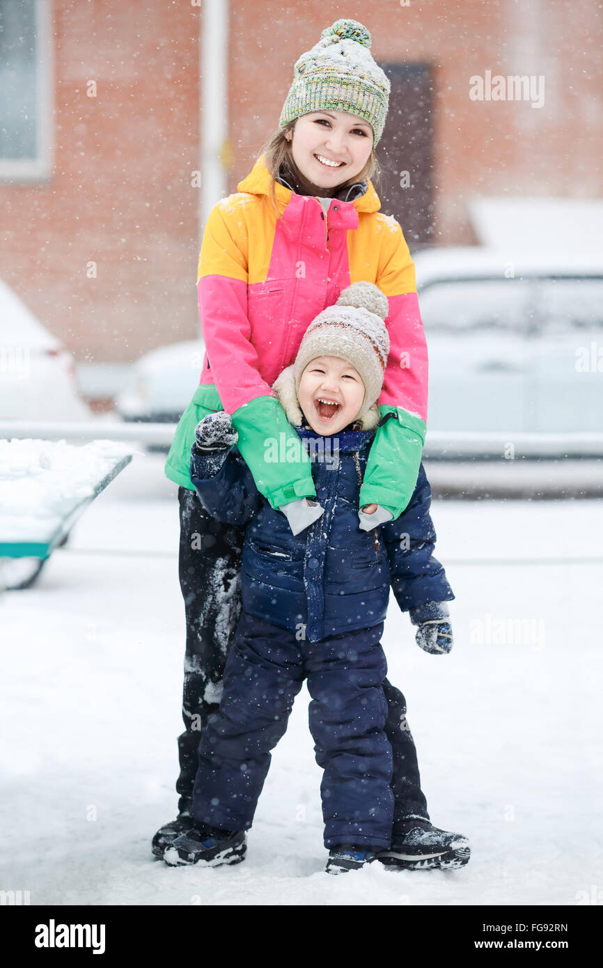 Madre con bambino sulla passeggiata invernale, emozioni positive, all'aperto. Nevicata, Blizzard. Foto Stock