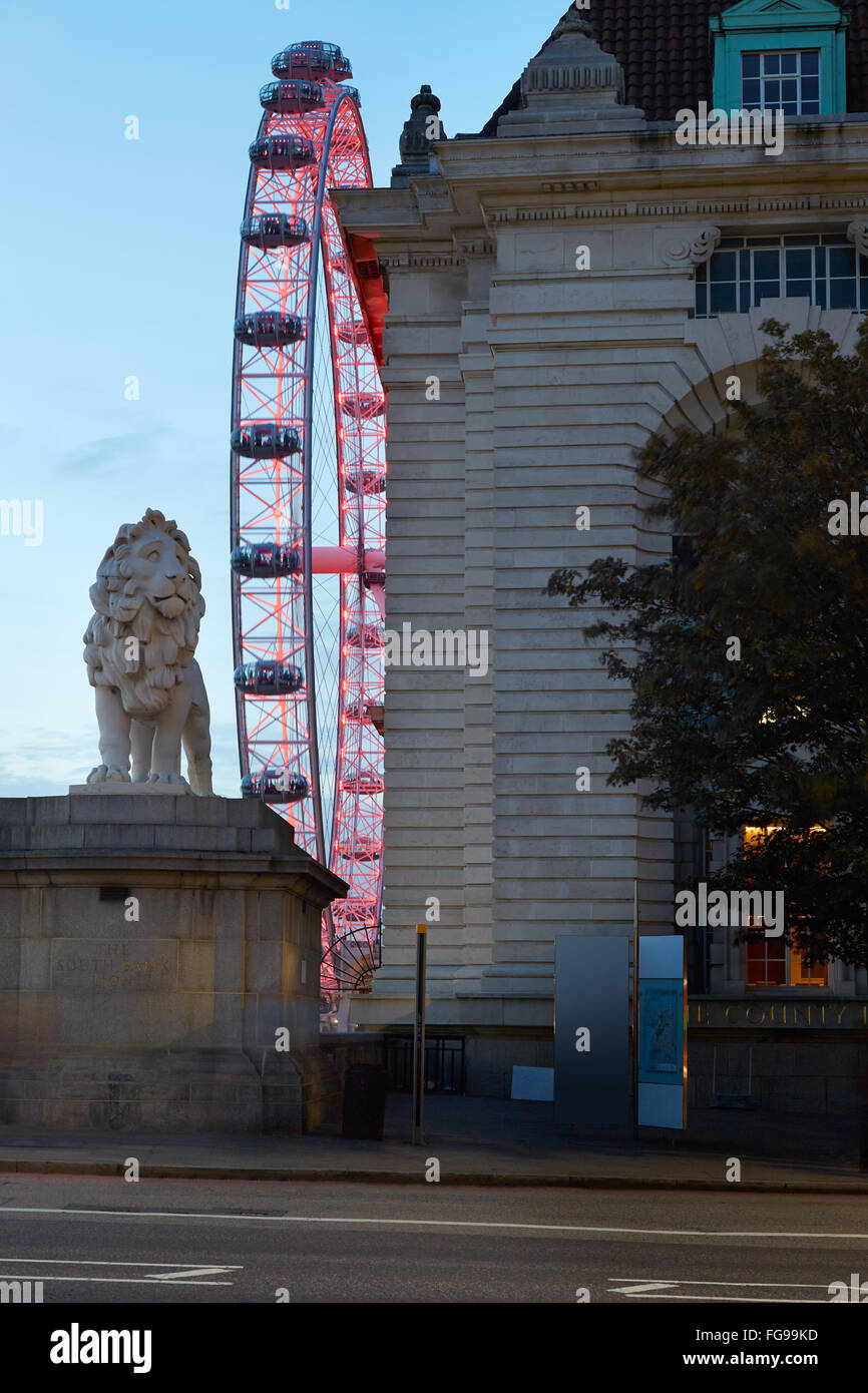 London Eye, ruota panoramica Ferris, illuminato in rosso nella notte e lion statua in Londra Foto Stock