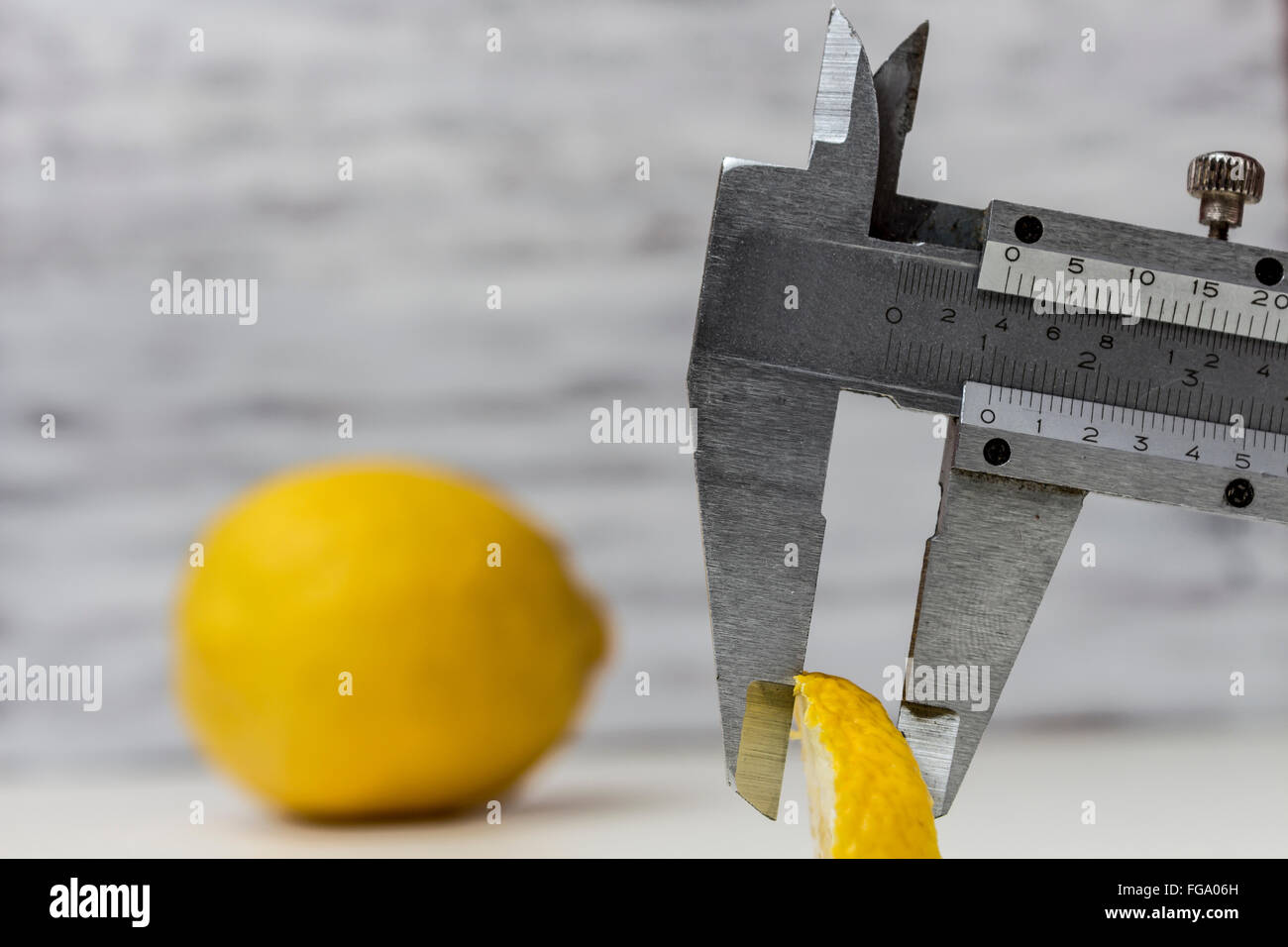 La misurazione di una fetta di limone con l'uso di un calibro a corsoio Foto Stock
