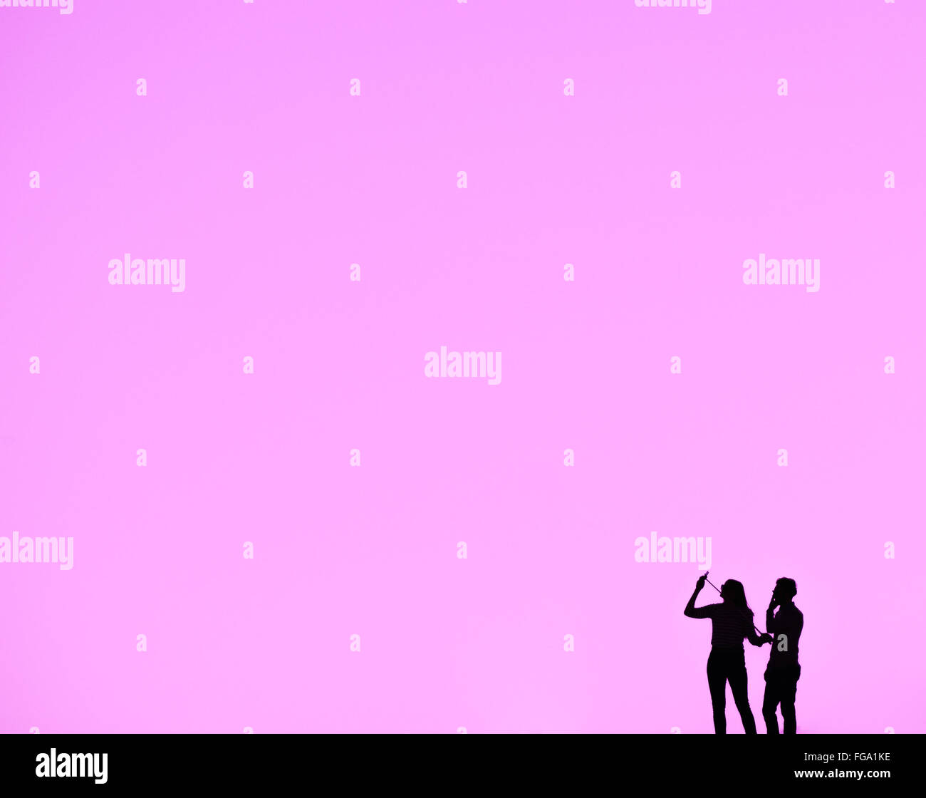 Silhouette Uomo e donna in piedi contro il cielo rosa Foto Stock