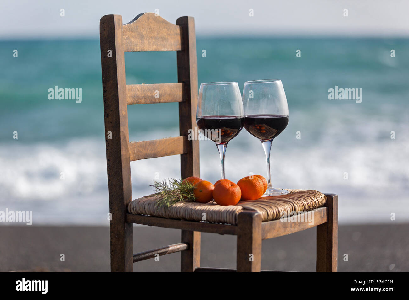 Vino e tangerini su una sedia contro il mare Foto Stock