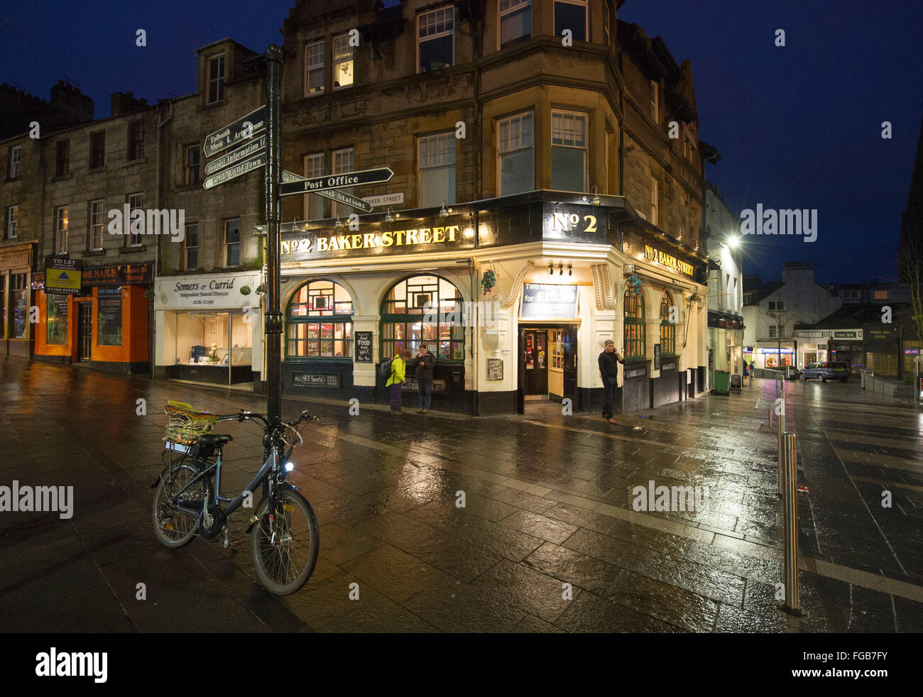 4. febbraio 2016, Baker Street, Stirling, Scozia, scena notturna, noleggio si appoggia contro un cartello stradale vicino n. 2 Baker Street pub. Foto Stock